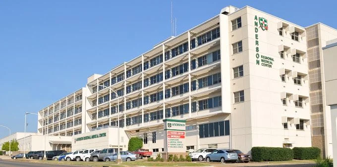 White multi-story hospital building with parking lot