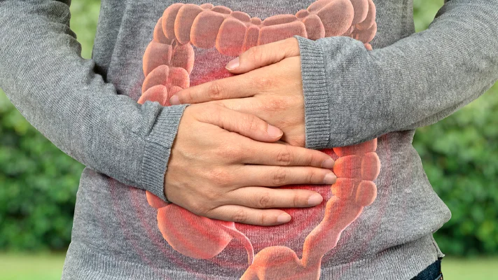 Person holding stomach, graphic of intestines overlayed.