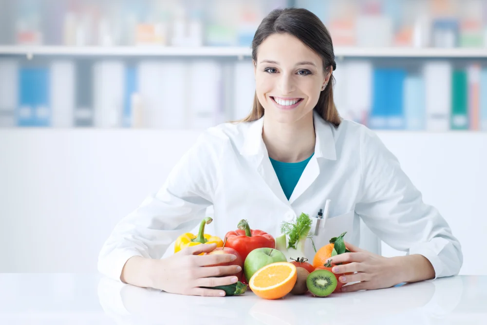 Smiling nutritionist with fresh fruits and vegetables.