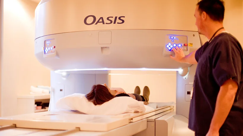 Technician operating MRI machine with patient lying down.