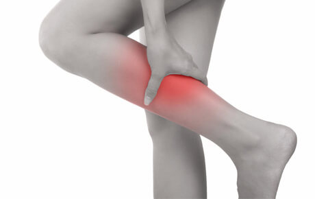 Person holding sore knee, pain highlighted in red.