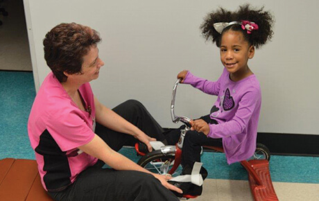 Child receiving physical therapy with tricycle.